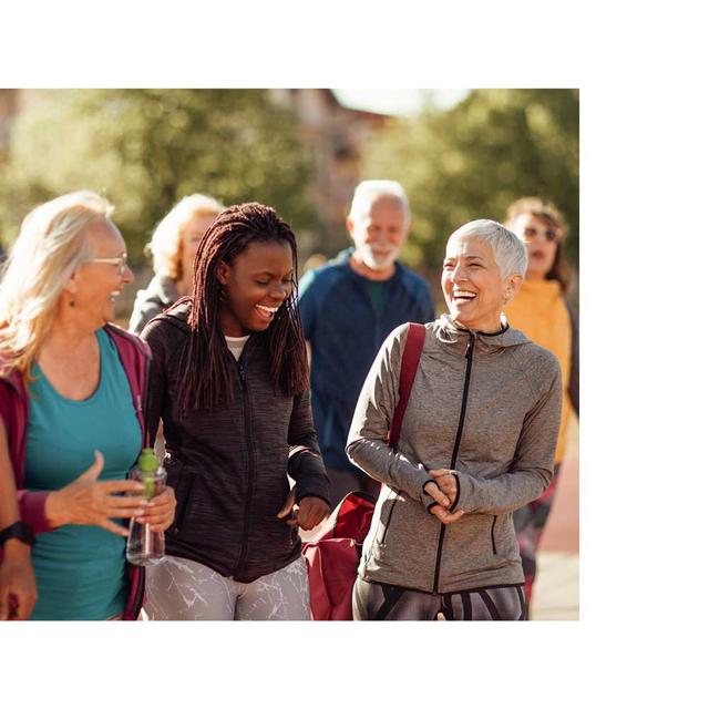 A group of diverse community members walk together, laughing and smiling outdoors.