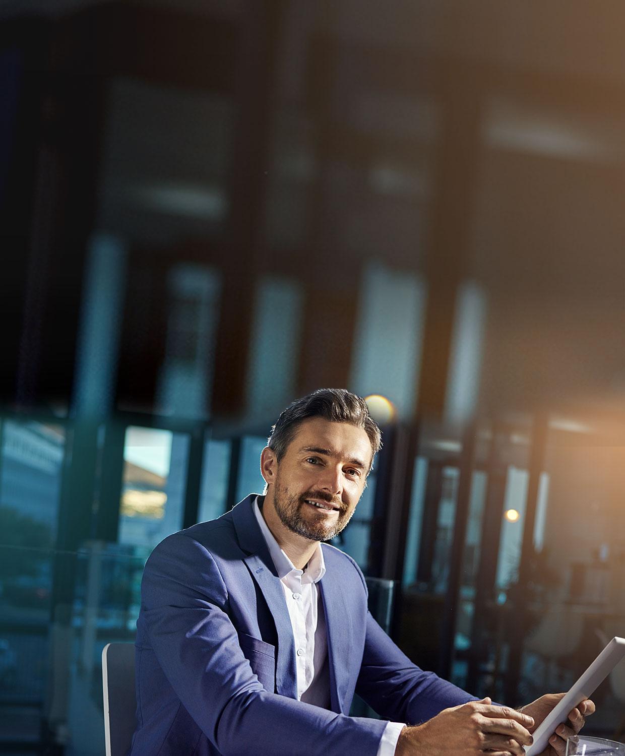Man wearing a sports jacket with collared shirt sitting at desk with laptop open with CentralSquare Solutions on screen