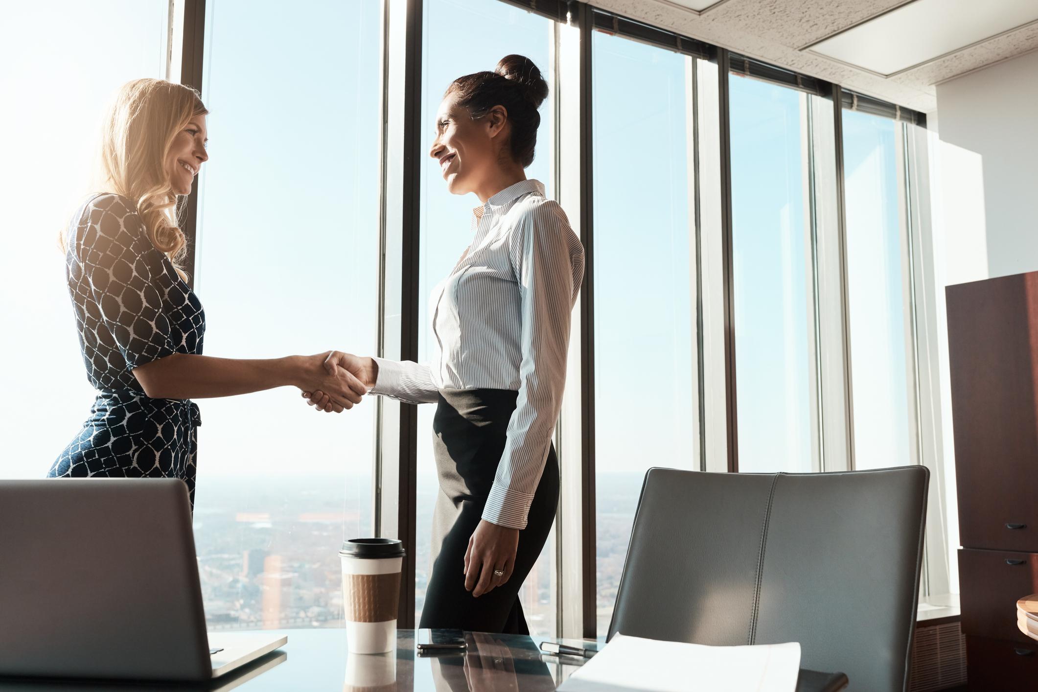 Two businesswomen shaking hands discussing CentralSquare