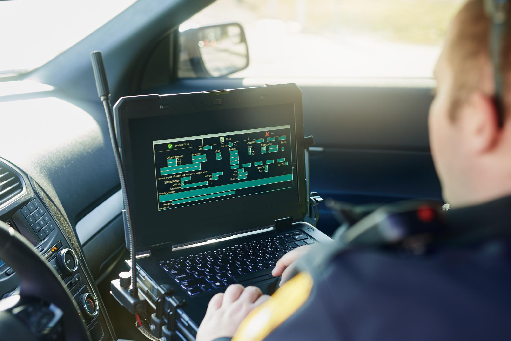 A police officer completing an incident report in his vehicle.