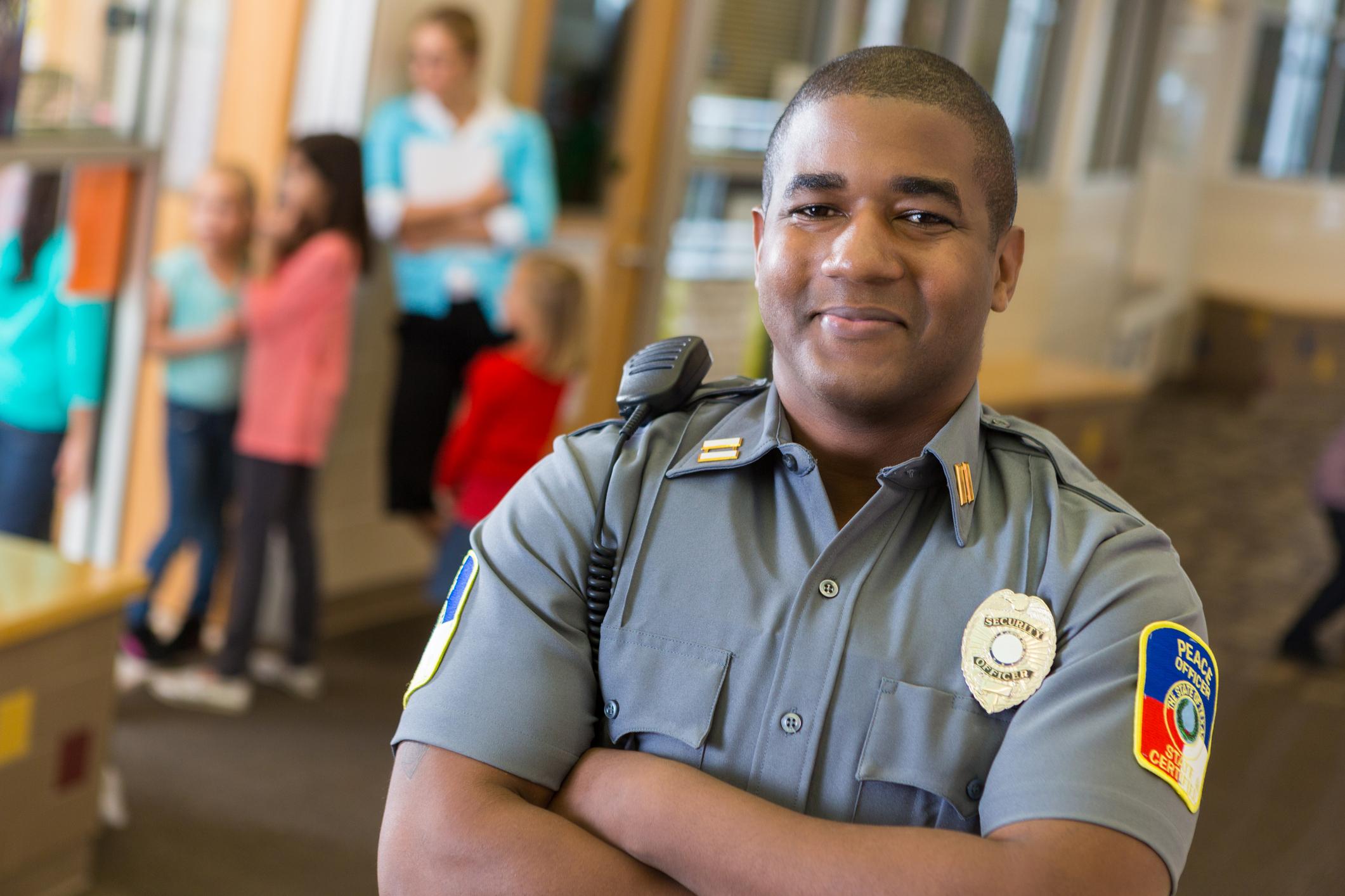 A school resource officer with a classroom of students in the background.