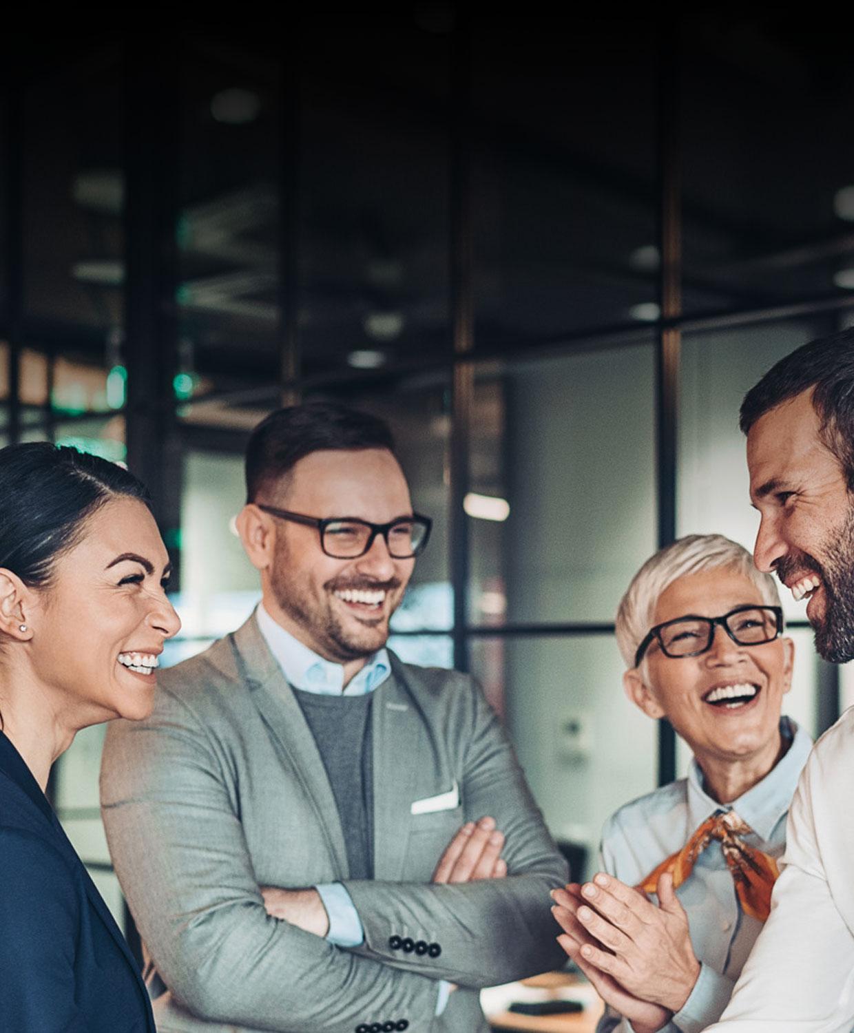 A background image of a group of professional individuals standing and chatting together in an office setting. They are smiling.