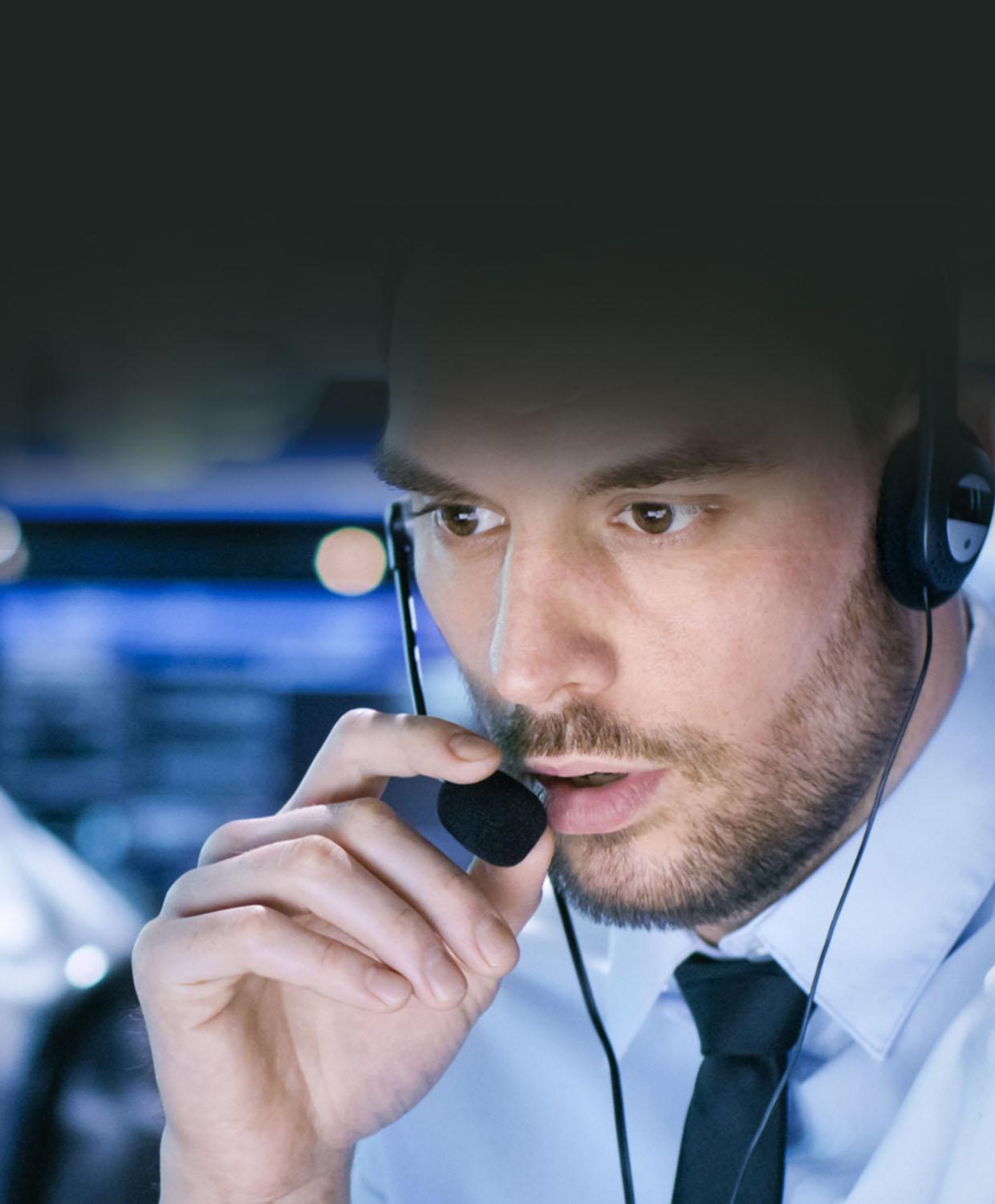 A woman working in a 911 Dispatch Center is talking over a headset.