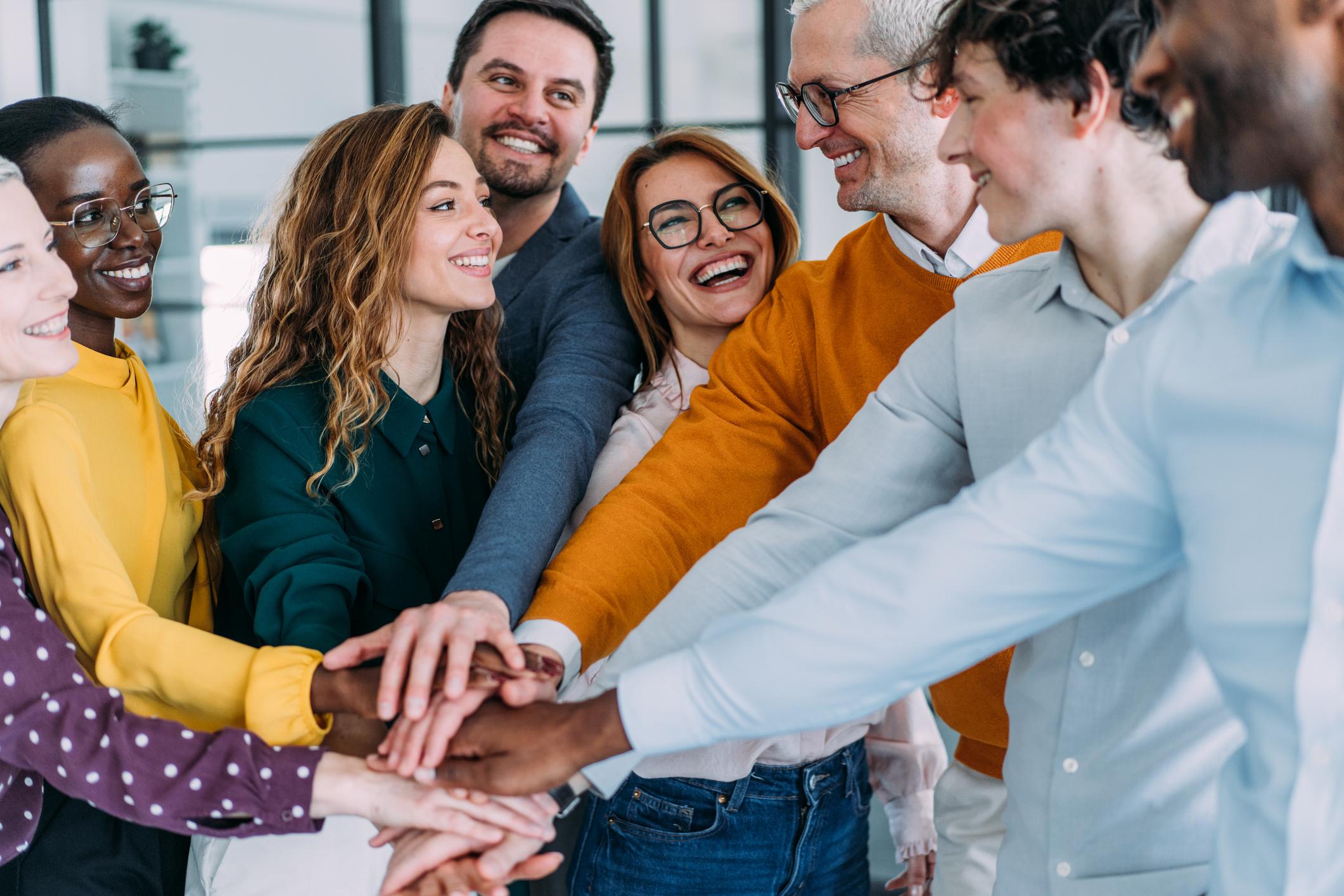 Group of people with stacked hands showing unity and teamwork.