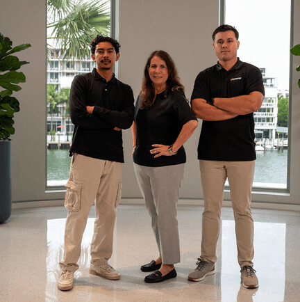 Two men and a woman standing in an office looking at camera and smiling