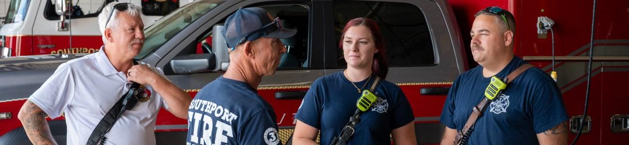 Four firefighters in front of a fire truck