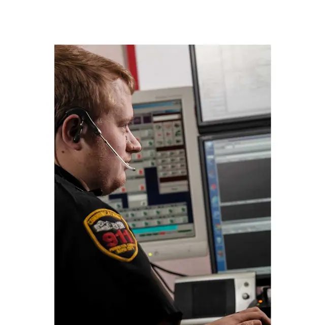 A telecommunication dispatcher with a headset on responding to a call.