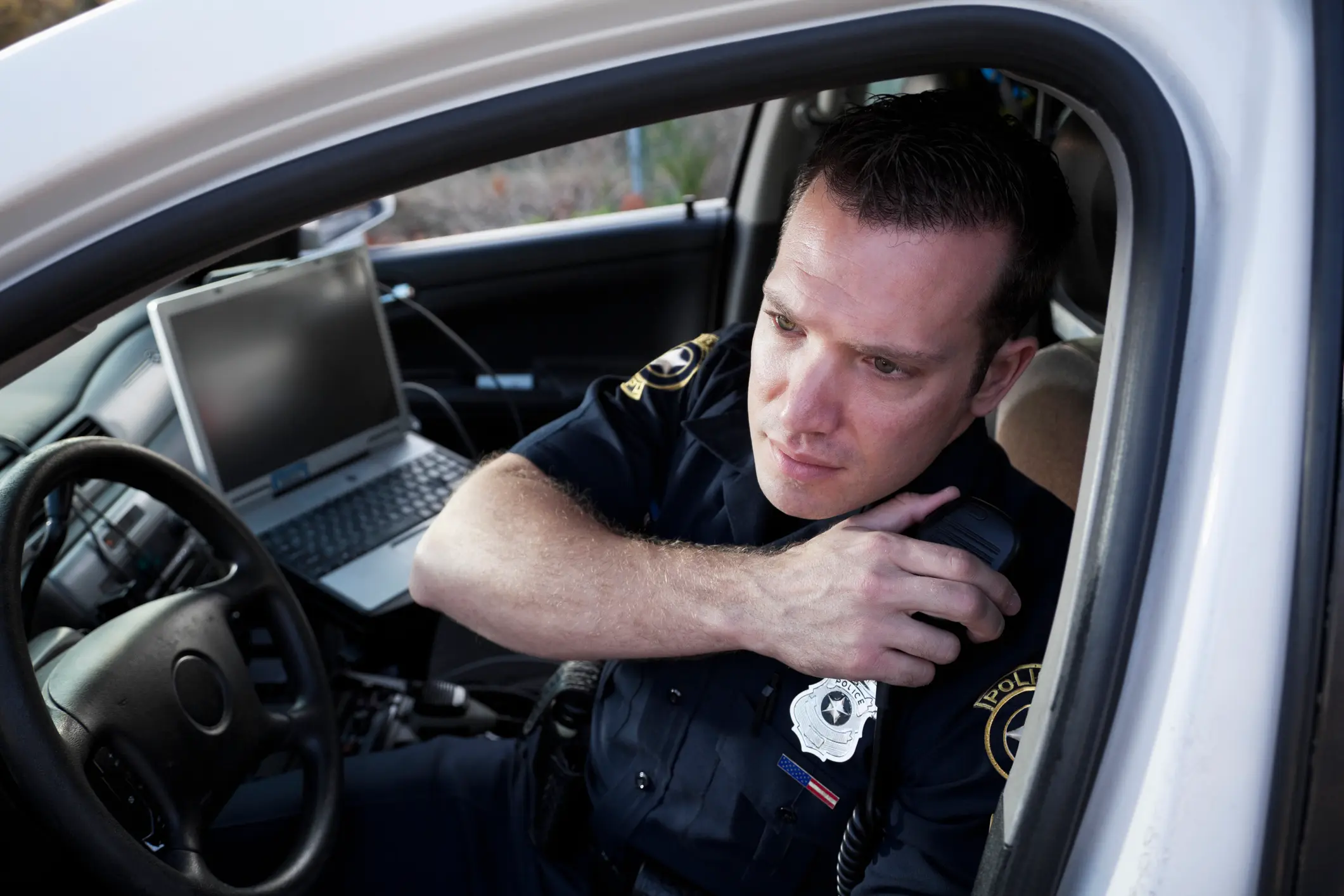 police officer sitting in car with laptop